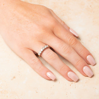 Hand featuring an 18ct yellow gold six stone diamond ring on a light background